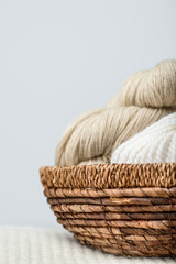 close up view of yarn clews in wicker basket on grey backdrop