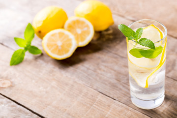 Fototapeta premium Lemon water with fresh lemons and green mint on table