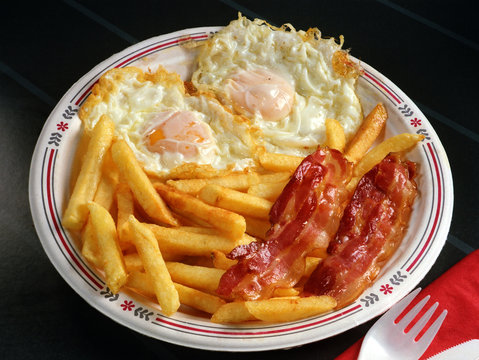 Plato combinado con dos huevos fritos, beicon y patatas fritas.