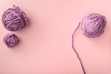 Obraz premium top view of purple knitting balls on pink tabletop