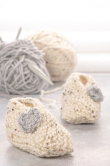 Obraz na płótnie Canvas Knitting baby booties and wool yarns on soft background. Hand-made socks for the baby.