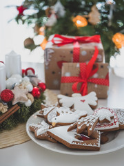 Christmas gingerbreads, candles, and Christmas bell. In background Christmas tree.