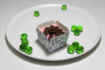 Pink strawberry cupcake and topping with chocolate and jelly green round in the white dish on the white floor.