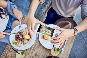 Overhead view of couple taking photo of food at outdoors restaurant