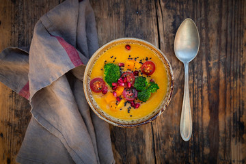 Bowl of curry dish with Hokkaido pumpkin, broccoli, tomatoes, pomegranate seed and black sesame