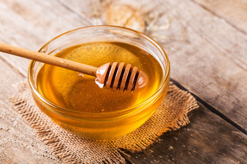 Fresh honey with stick in glass bowl 