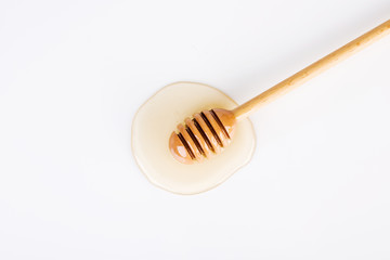 Top view of honey and honey dipper on white background