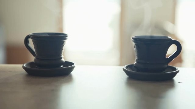 Waiter bringing a fresh maiden coffee in black clay cup and putting on table close up view. Coffee consummation in modern coffee shop concept cinematic Slow motion footage.