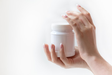 hands holding white plastic container, round can on hand, close container with medicaments isolated on white background