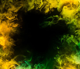 frame from yellow and green smoke over black background