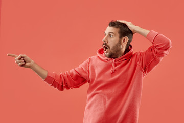 Wow. Attractive male half-length front portrait on coral studio backgroud. Young emotional...