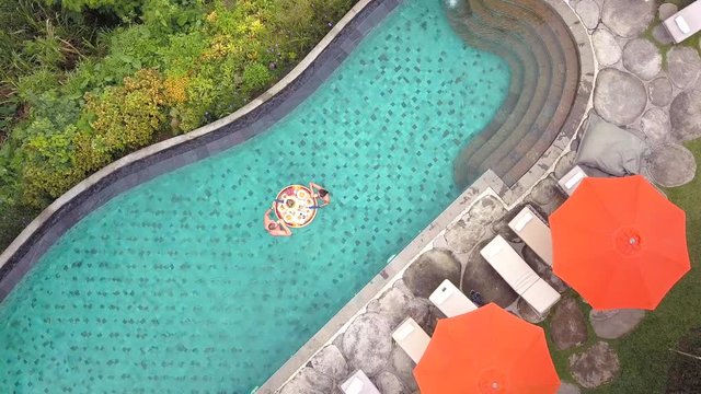 Aerial Top View: Young Couple Clinking Cocktails and Having Floating Breakfast in Swimming Pool. Tropical Vacation Travel Holiday Concept. 4K. Bali, Indonesia.