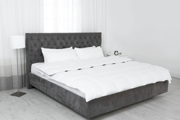 Large comfortable bed in light room. Stylish interior