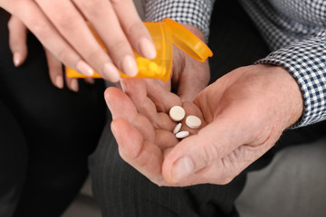 Woman giving pills to senior man, closeup