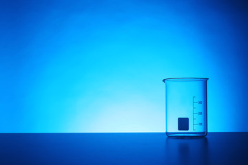 Empty beaker on table against color background. Chemistry laboratory glassware