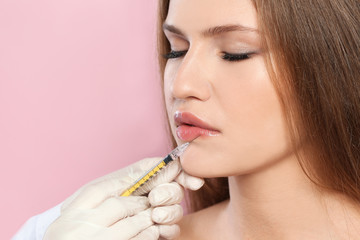 Young woman getting lips injection on color background, space for text. Cosmetic surgery