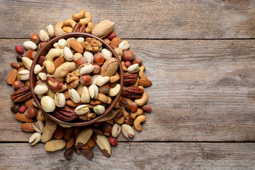 Flat lay composition with mixed organic nuts and space for text on wooden background, top view