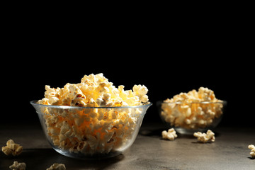 Tasty popcorn in bowl on table against black background. Space for text