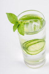 Slices of fresh cucumber in glass cup with ice cubes and fresh mint, close up