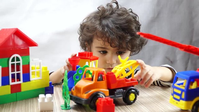 Blond little boy playing with colorful plastic toys. 4K
