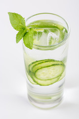 Slices of fresh cucumber in glass cup with ice cubes and fresh mint, close up