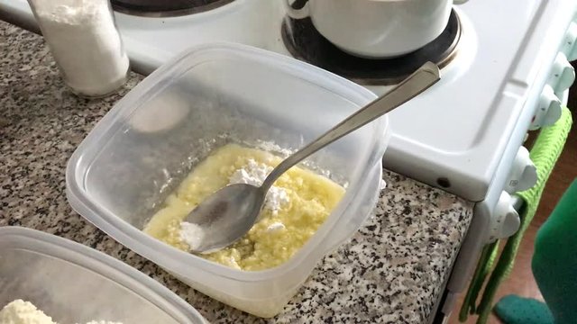 A woman adds vanillin to a container of melted butter and icing sugar. Ingredients for dessert.