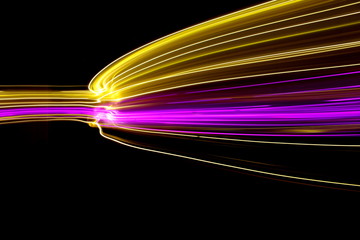 Long exposure, light painting photography. Pink and gold neon streaks of vibrant color against a black background 
