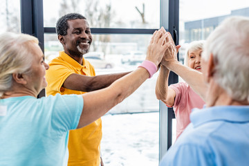 Fototapeta premium selective focus of senior multicultural sportspeople putting hands together at gym