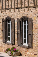 Fototapeta na wymiar a brick wall with windows and wooden shutters