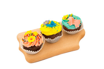 freshly baked muffins with cream and glaze and pile of fruit, black, green tea on the wooden board