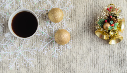A Cup of coffee ,decorated snowflakes, two pair Christmas golden balls and Christmas toy on a light wool sweater.Winter concept.