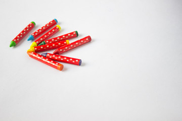 Jumbled group of multi-coloured wax crayons on white 