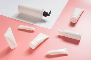 Cosmetic products collection. Blank white cosmetic bottle/tube on pink and white background. Branding mock-up for lotion, cream, gel, foam, soap or shampoo. Minimal style. Beauty blogger concept.