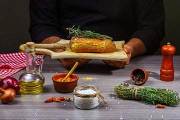 men's hands, close-up, holding meat steak, herbs and spices on wooden table, home cooking concept