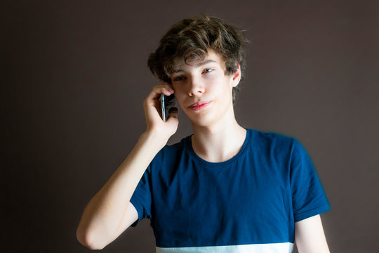 young male teenger talking via new smartphone isolated on dark mackground, studio shot f