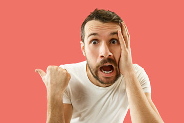 Wow. Attractive male half-length front portrait on coral studio backgroud. Young emotional...