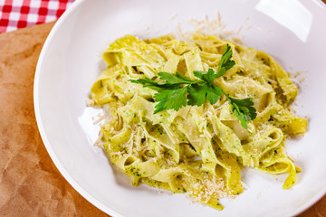 Italian Pasta tagliatelle with pesto sauce and parmesan cheese on white plate. Close up