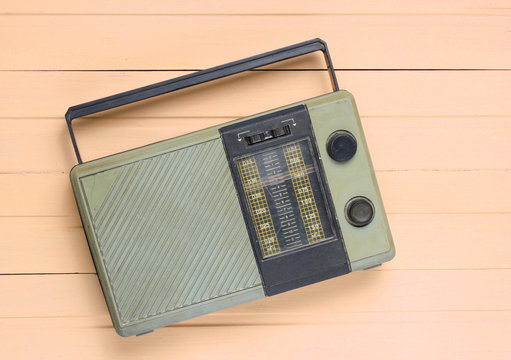 Retro old radio receiver on yellow wooden background. Top view. Outdated technology.