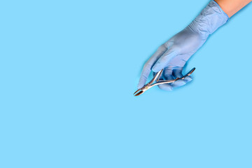 master nails in blue gloves holds manicure tool. set of manicure accessories on blue background top...