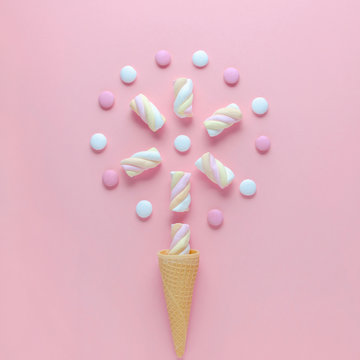 candy, marshmallow and ice cream waffle cone on pink background, concept image, view from top