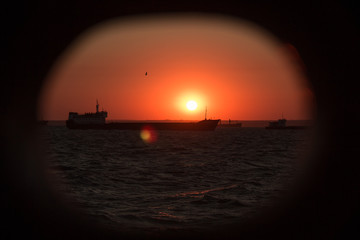 Obraz premium cargo ship outgoing from port at sunrise
