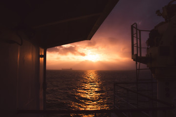 cargo ship outgoing from port at sunrise