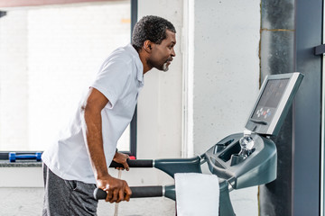 side view of mature african american sportsman running on treadmill at gym