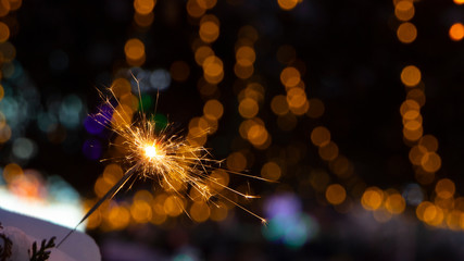 burning sparkler on bokeh background from lights of garland