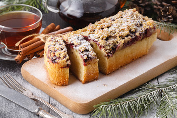 Traditional Christmas cake with dried fruits, raisins and a cup of tea on a wooden table with Christmas decorations