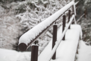 the handrail for the stairs in the snow. road after snowfall. winter way home.