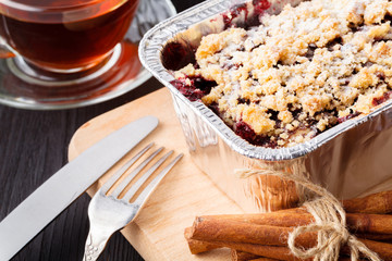 Traditional Christmas cake with dried fruits, raisins and a cup of tea on a wooden table with Christmas decorations