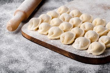 Homemade raw dumplings, pelmeni, on wooden background