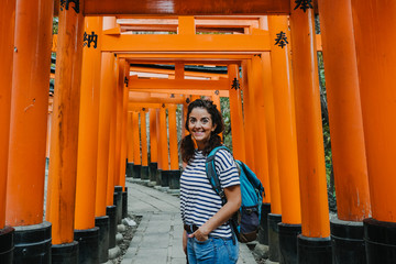 Fototapeta na wymiar Young occidental woman doing sightseeing in the Fushimi Inari-taisha shrine in Japan. Walking the long way to the top full of red torii. Travel photography. Lifestyle.