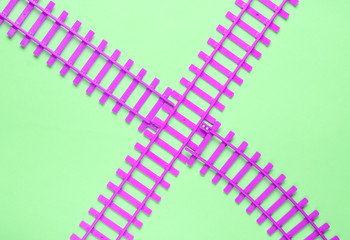 Toy railroad tracks on green pastel background. Top View.